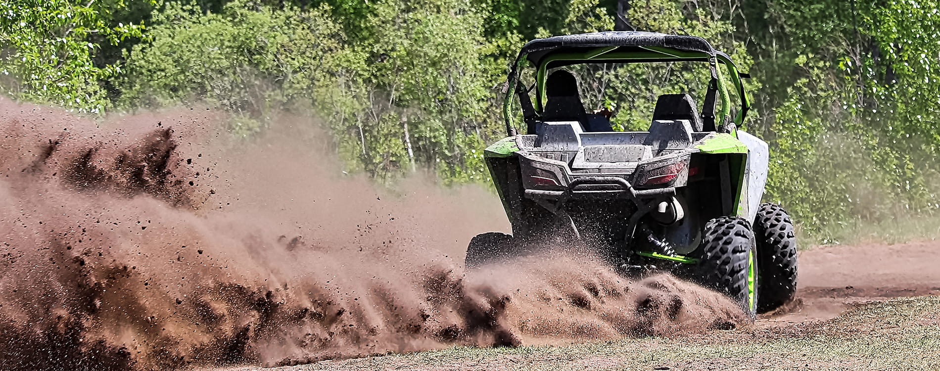 UTV riding through terrain with a large dust cloud